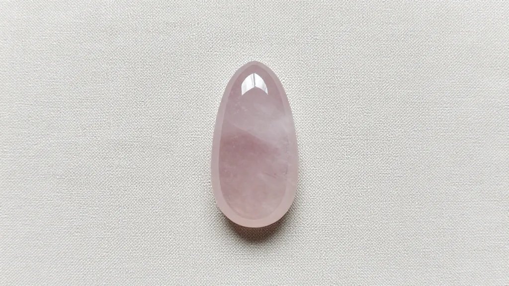 single raw rose quartz pendant on soft linen backdrop