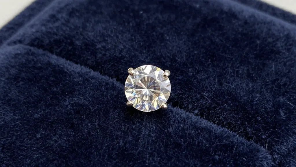 single sapphire solitaire stud earring on velvet backdrop