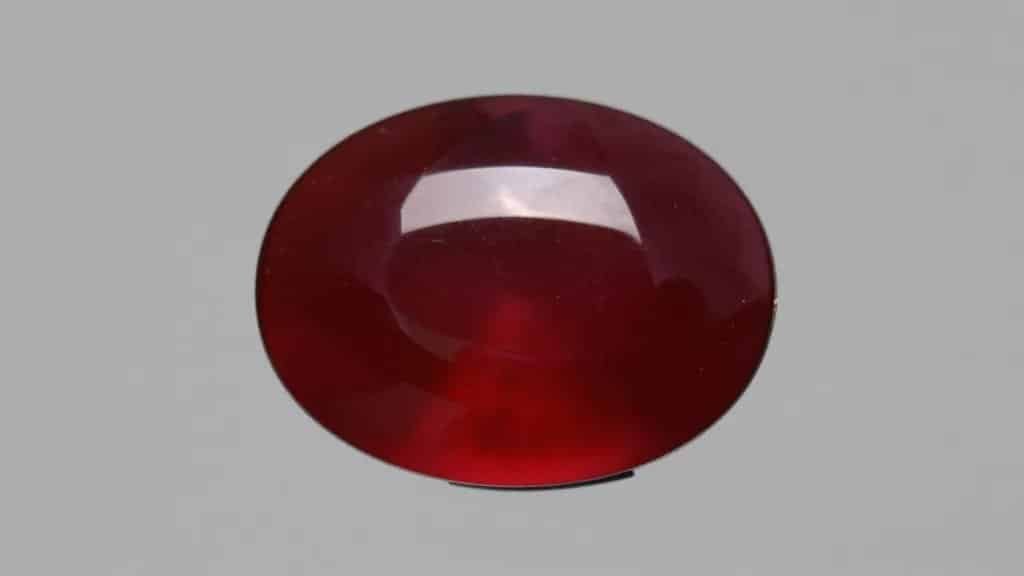 silky-glow Burmese ruby cabochon on neutral gray backdrop