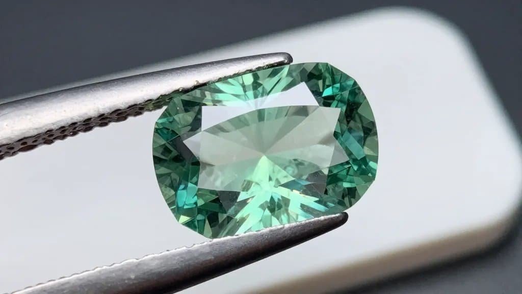 mint green tourmaline emerald-cut on white grading tray, closeup