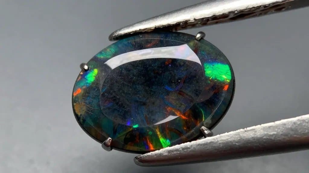fiery black opal cabochon, macro shot, play-of-color