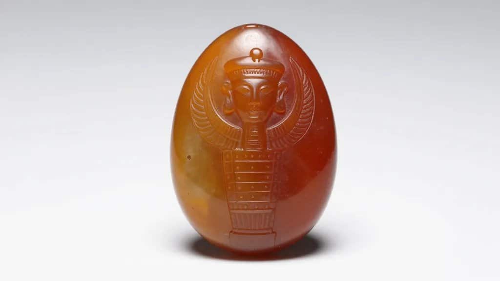 closeup of a single carved Egyptian carnelian amulet, studio-lit