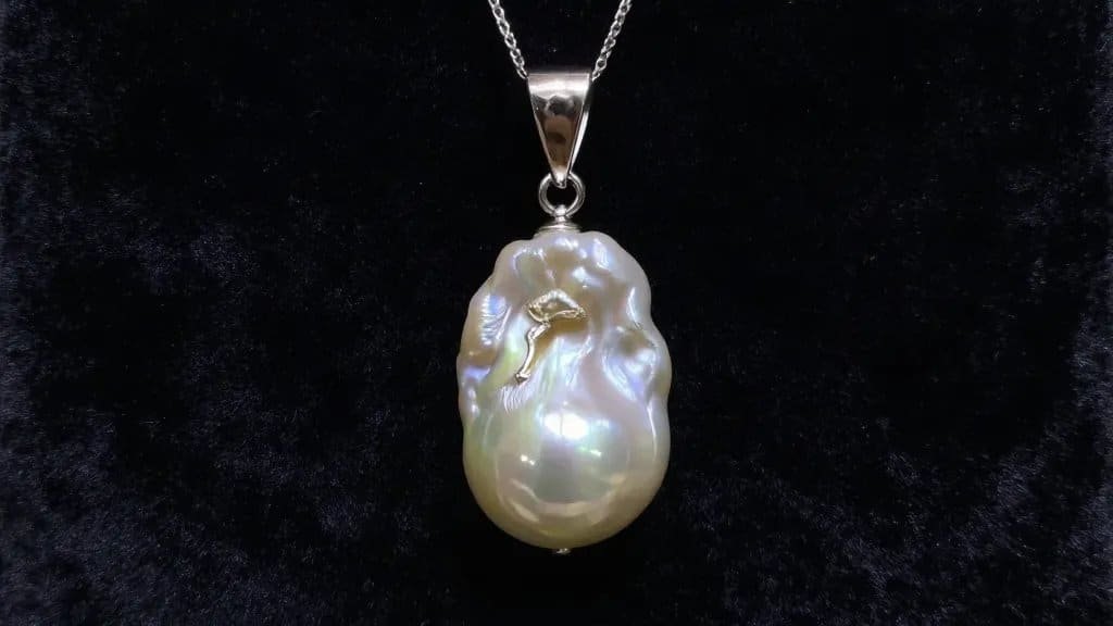 Single baroque pearl pendant, dramatic side lighting, velvet backdrop
