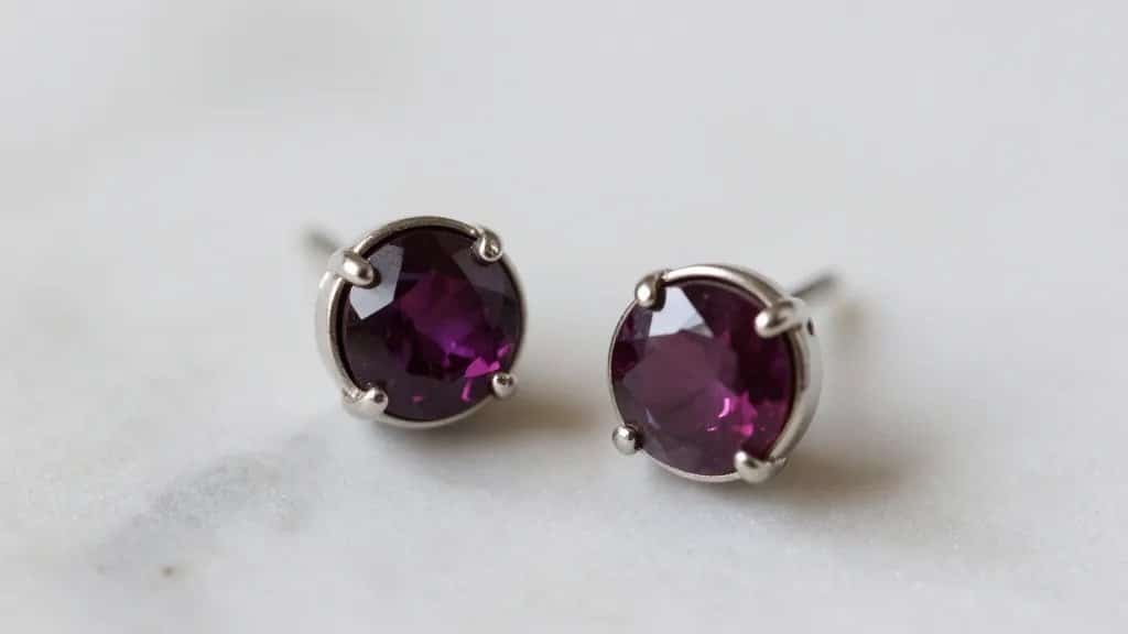 closeup of garnet stud earring in bezel setting on marble
