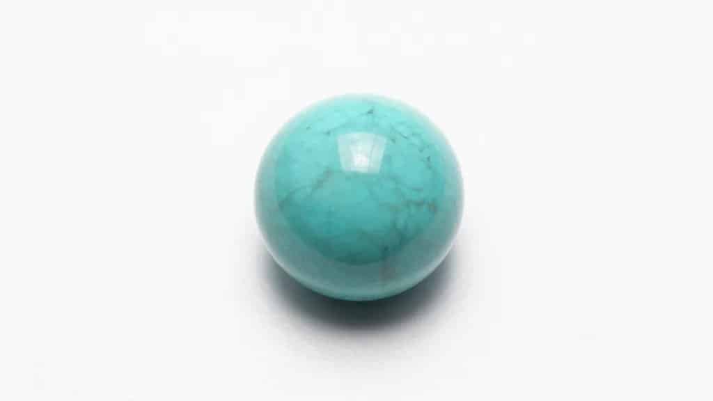 Single polished turquoise cabochon on white background