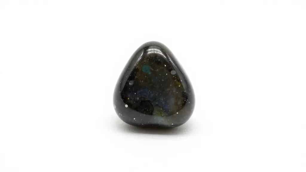single tumbled obsidian cabochon on white backdrop