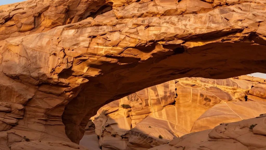 closeup of iron-stained sandstone arch catching golden sunlight